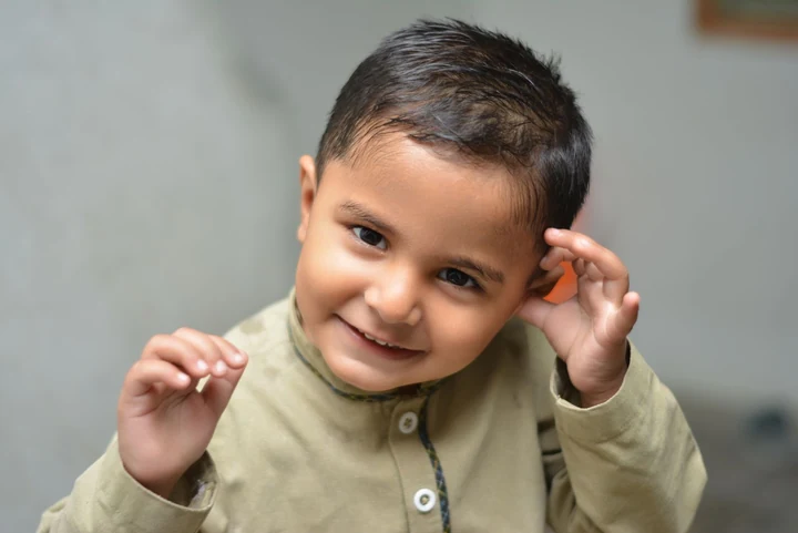 Licensed stock photo used for fictional Sami: a smiling child with short dark hair and a pale green shirt.